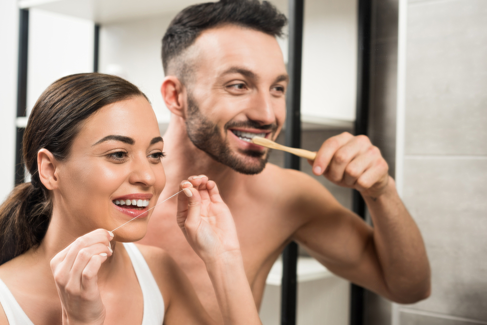 Bearded Boyfriend Brushing Teeth Near Girlfriend Using Dental Floss In