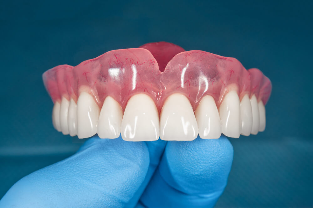 Full removable denture of the upper jaw of man with white beautiful teeth in the hand